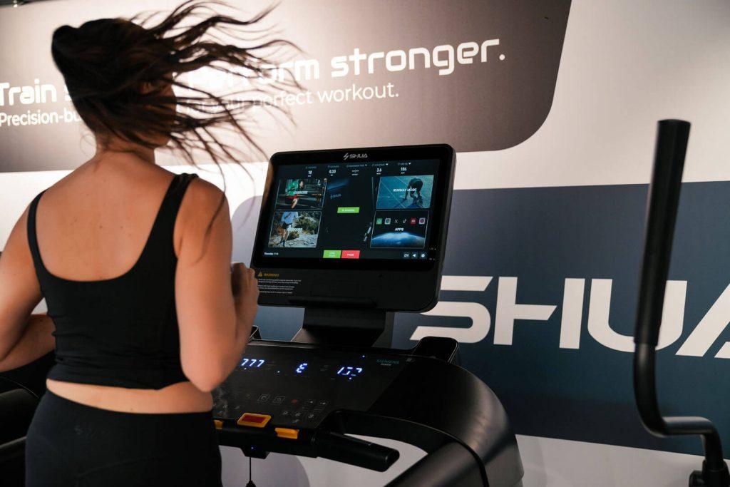 Ženska z dolgimi lasmi teče na fitnes napravi