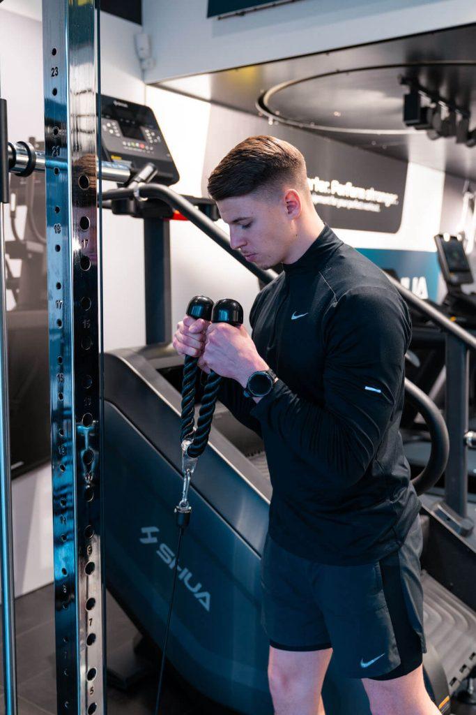 Mlad moški uporablja večnamensko fitnes napravo Shua za trening