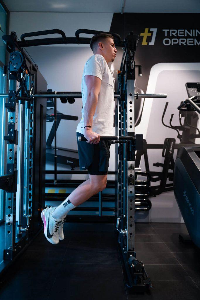 Mlad moški uporablja večnamensko fitnes napravo Shua za trening